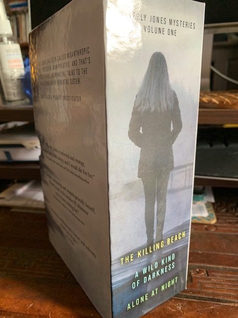 Side and back cover for the boxset. Young woman with long hair looking out at water on a dock and the book titles.
